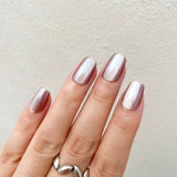 Hand with metallic pink nail polish on a neutral background