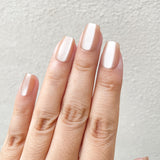 Close-up of a hand with light pink nail polish on a neutral background