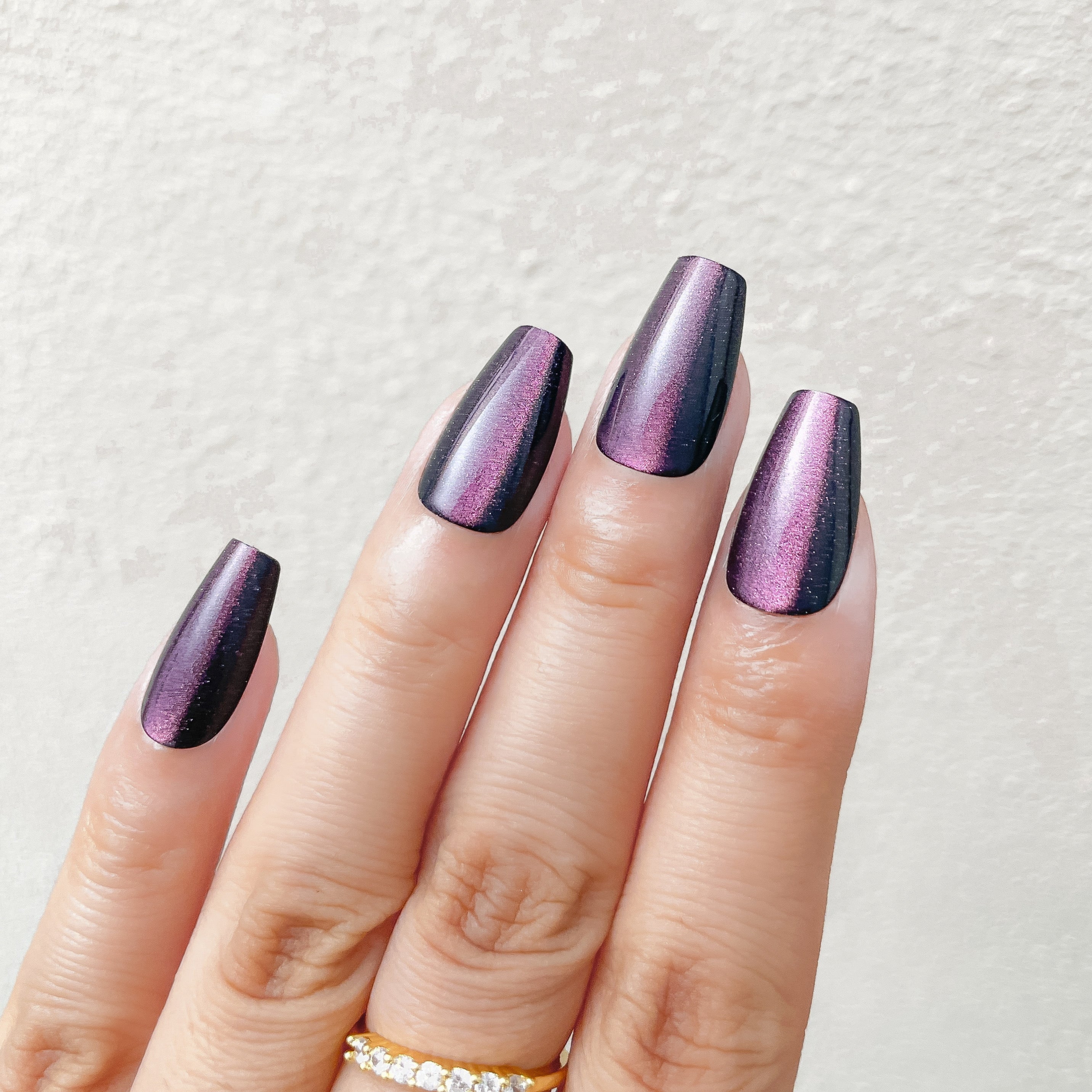 Hand with purple and black gradient nails on a light background