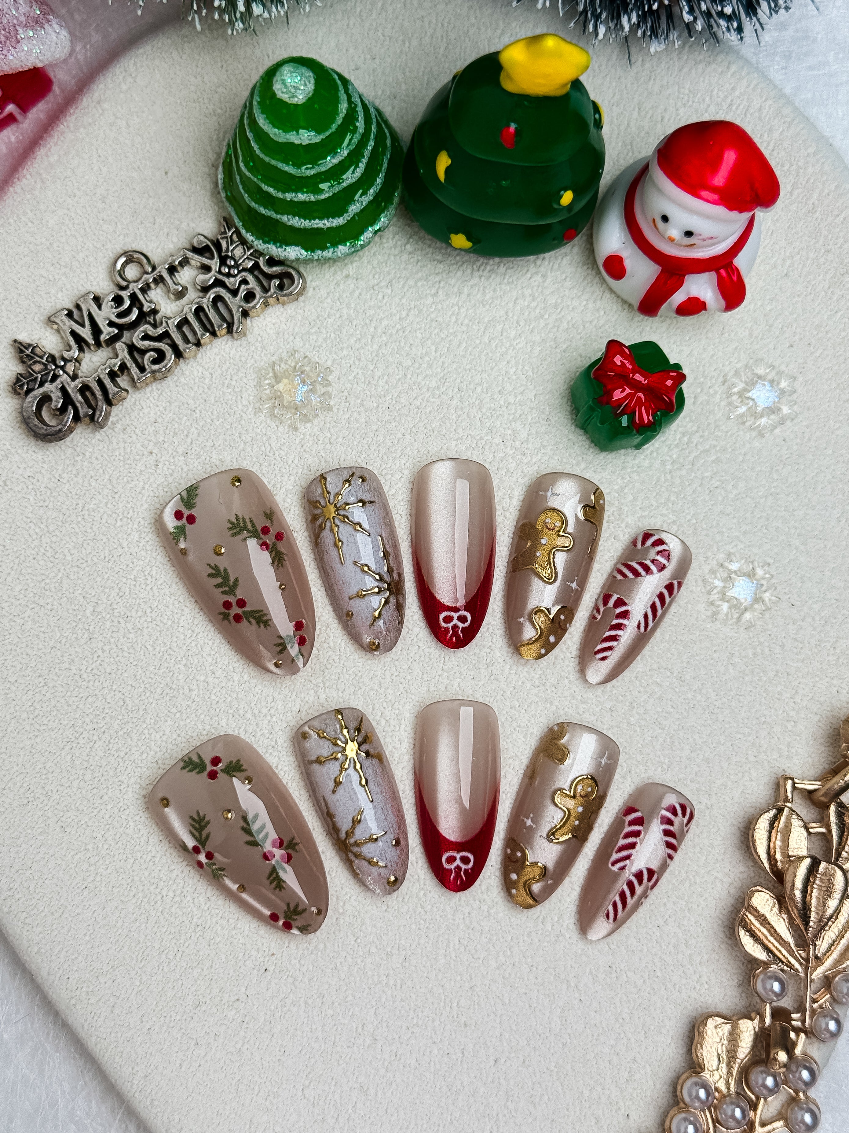 Christmas-themed nail art designs on a white surface with decorative items.