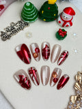 Christmas-themed nail art with red, silver, and gold decorations on a white background.
